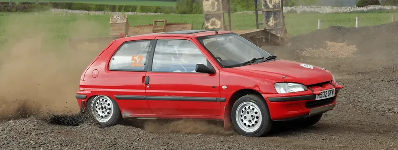 Red hatchback on a loose surface stage