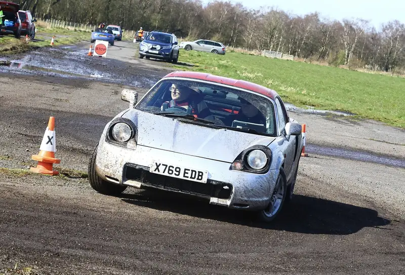 Silver sports car negotiating cones at an autotest