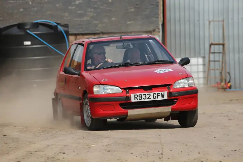 Red hatchback rally car on a gravel stage